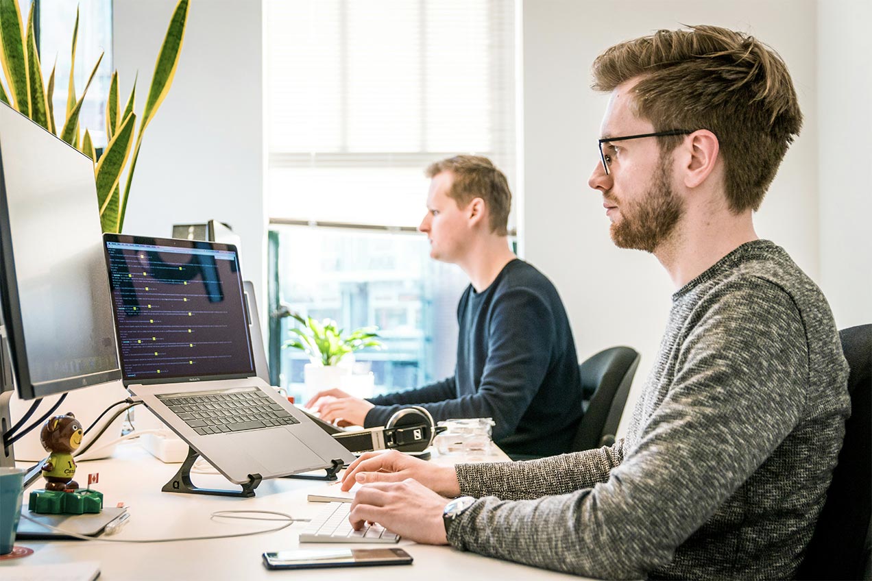 image of two software developers working on a desk looking at a computer screen